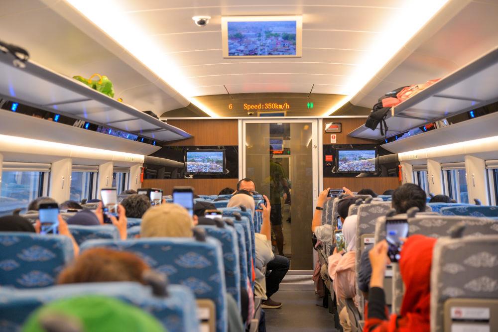 △2023年11月5日，在行驶中的雅万高铁高速动车组列车车厢内，乘客纷纷用手机拍摄显示列车时速达到350公里的电子屏。